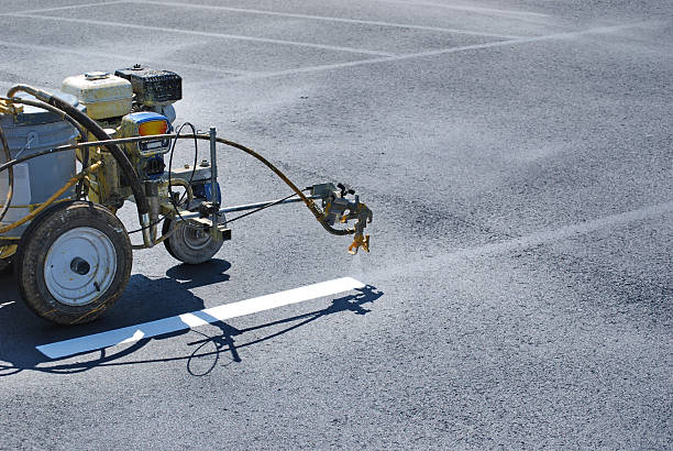 Striping machine painting lines onto fresh asphalt.